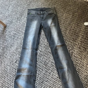 Grå bootcut jeans med slitningar - Snygga grå jeans med bootcut-modell och diskreta slitningar längs benen. Jeansen har klassisk femficksdesign och är tillverkade i ett mjukt jeansmaterial. Perfekta för dig som gillar en lite vidare passform nertill och vill ha en cool, avslappnad look.