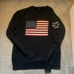 USA Gant tröja - Säljer en blå stickad tröja från Gant med broderad USA flagga på bröstet och vit text på ena ärmen. Tröjan har rund hals, ribbade muddar och lång ärm! Perfekt för dig som gillar klassisk collage-stil och snygg detaljer. Storlek M men kan passa S med! Den är ungefär 170cm lång! Hör av er vid snabb affär då pris kan diskuteras!!
