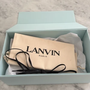 Lanvin sko kartong st - Lanvin skokartong i hyfsat bra skick. Skorna som tillhör kartongen är ett par svarta med glansig tå, i storlek 7. Du mer med dig lådan, pappret dustbagen och extra skosnören. Säljer till någon som vill ha en box till sina skor eller om nån är sugen på sälja vidare sina skor men har ingen låda och vill tjärna liten extra peng!