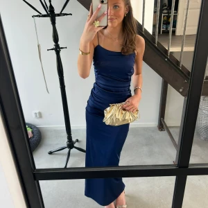 Marinblå balklänning  med öppen rygg - Säljer min marinblåa balklänning med smala axelband och  öppen rygg. Klänningen har en tight passform och är tillverkad i ett glansigt, stretchigt material. Perfekt för bal,nyår, bröllop mm. Endast använd en gång på balen i 9an! Nypris 900kr men säljer nu för 600kr!