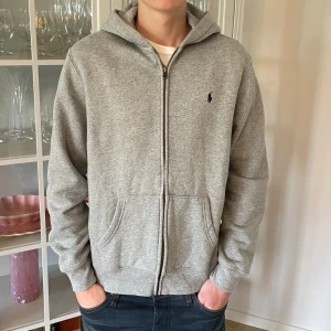 Grå hoodie från Polo Ralph Lauren - (18-20) S - Jag säljer den här riktigt fina gråa Polo Ralph Lauren hoodien. Den är knappt använd och i väldigt bra skick utan defekter och skador. Den är i storlek 18-20 vilket jag skulle säga motsvarar S. Tveka inte att höra av er!