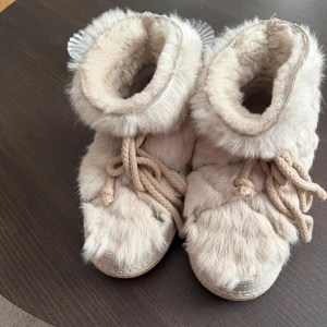  Inuikii - Säljer ett par supermysiga boots från Inuikii i beige med pälsdetaljer och snörning framtill. Skorna har en rund tå, platt sula och är fodrade med mjuk päls för extra värme. Perfekta för kalla dagar och ger en riktigt trendig vinterlook. I fint skick.💕