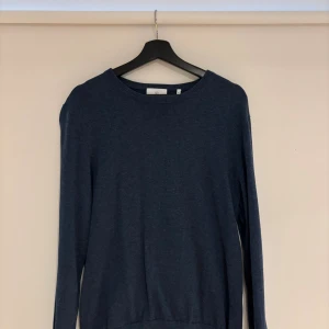 Mörkblå stickad tröja från Bläck - En stilren mörkblå stickad tröja från Bläck i storlek M. Tröjan har rund halsringning, långa ärmar och ribbade muddar vid hals, ärmslut och nederkant. Perfekt för lager-på-lager och enkel att matcha med jeans eller chinos. Ganska stor i storleken, skulle mer säga en L eller större M. 