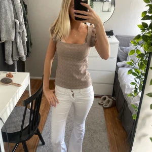 Beige smockad topp med fyrkantig ringning - Säljer en beige topp med smockat tyg och fyrkantig ringning. Toppen har korta ärmar och sitter figurnära utan att vara för tight. Perfekt till jeans eller kjol för en enkel men snygg look.