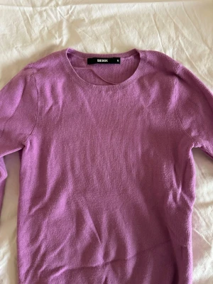 Rosa stickad tröja från Bik Bok - Enkel och snygg rosa stickad tröja från Bik Bok i storlek M. Tröjan har rund halsringning och långa ärmar. Den är liten i storleken och passar bättre för dig som vanligtvis har storlek S eller XS