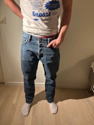 Weekday Barell jeans - Klassiska blå weekday jeans med rak passform och knappgylf. Jeansen har fem fickor och tydliga kontrastsömmar. Tillverkade i slitstarkt denimtyg som ger en tidlös look. Perfekta för dig som gillar en avslappnad och autentisk jeansstil.