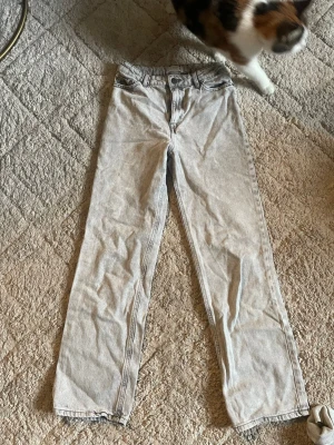 Ljusgrå raka jeans från Lindex - Säljer ett par ljusgrå jeans från Lindex med klassisk femficksmodell och raka ben. Jeansen har normal midja och är tillverkade i mjukt denimtyg. Perfekta för en avslappnad och stilren look.