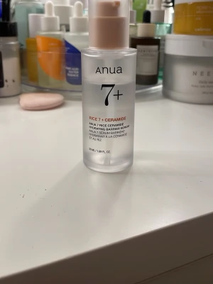 Anua Rice 7+ Ceramide toner - Anua Rice 7+ Ceramide Hydrating Barrier Serum i en frostad plastflaska med pump. Innehåller 50 ml och är perfekt för att återfukta och stärka hudbarriären. Flaskan är genomskinlig med svart och kopparfärgad text.