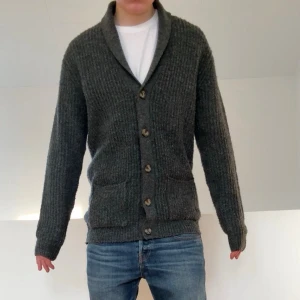 Grå Cardigan - Säljer en sjukt fet cardigan från S.C.W  i färgen grå. Tröjan är i bra skick och därav inga defekter på den. Den är i strl M och den sitter även som M. Hör gärna av er vid frågor eller funderingar 
