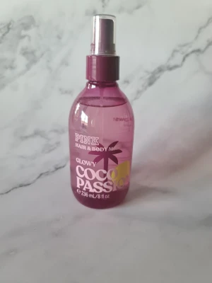 Glowy Coco Passion Hair & Body Mist - Fräsch hår- och kroppsmist från PINK, volym 236 ml. Vegansk, dermatologiskt testad och fri från artificiella färgämnen. Mot djurtester och förpackad med återvunnet material. Ingredienser: vatten, glycerin, parfym, propylenglykol m.fl. Tillverkad av Victoria's Secret Beauty Co. Endast testad några gånger