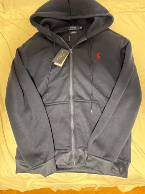 Polo Ralph Lauren hoodie - Nytt skick men som du ser på andra bilden syns det att polo ralph lauren lappen rev och det var där taggen föll av tyvärr