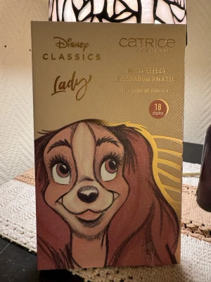 Disney Classics Lady ögonskuggspalett - En färg testad. Säljer en Disney Classics Lady Multi Effect Eyeshadow Palette från Catrice med 18 olika nyanser. Paletten har både matta och skimriga färger i bruna, guldiga, gula och rosa toner. Snyggt guldig förpackning med spegel och Disney-motiv.