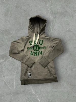 Grå hoodie från superdry SDU - En grå hoodie med grön text från superdry university! Priset är inte hugget i sten och går självklart att fråga om det är något du undrar över