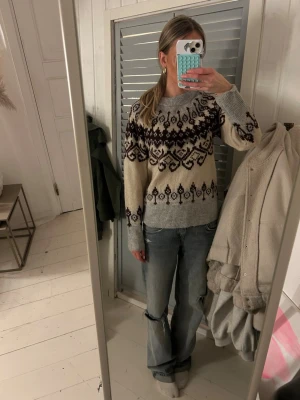 Mönstrad stickad tröja från Freequent - Säljer en stickad tröja från Freequent i storlek XS. Tröjan är beige och grå med mörkbrunt mönster över bröstet och ärmarna. Rund halsringning och långa ärmar med ribbade muddar. Perfekt för kyliga dagar och snygg till jeans.