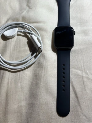 Apple Watch Series se 40 mm - Snygg Apple Watch Series se 40 mm svart aluminium med svart sportband (S/M). Klockan är i fint skick med endast mindre spår av användning. Original magnetisk laddkabel medföljer. Perfekt för träning, hälsa och notiser direkt på handleden.