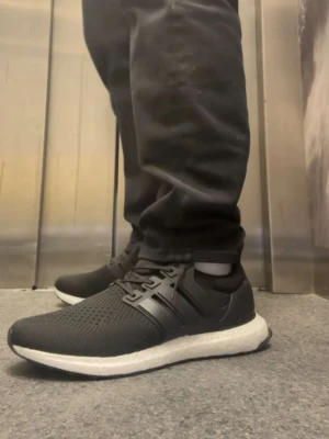 Svarta Adidas Ultraboost sneakers - Hejsan! Säljer ett par svarta Adidas Ultraboost sneakers med stickad ovandel och klassiska tre ränder på sidan. Skorna har vit, responsiv sula och svart yttersula. Perfekta för dig som vill ha både stil och komfort. Snörning framtill och sportig look. OBS-helt nytt!!Vid frågar och funderingar så är det bara att slå en pling! MVH