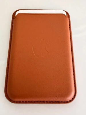 Apple iPhone Läder Wallet Plånbok med MagSafe Brown / Brun - Apple iPhone Läder Wallet Plånbok med MagSafe Brown, Brun  Håll ditt ID och dina kort nära till hands med denna stilrena plånboken  • Helt Ny/ Oanvänt • Ordpris: 599kr • Designad för att enkelt fästas på din iPhone med hjälp av MagSafe • Plånboken har starka inbyggda magneter så att den smidigt kan snäppas fast på baksidan av iPhone • Du kan även skapa en helt egen look genom att fästa den utanpå ett skal med MagSafe • Plånboken har plats för tre kort och är avskärmad från magneterna så dina kon