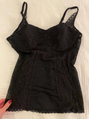 Svart spetslinne - Vintage Korsettliknande topp med spetsdetaljer. Sitter mer som ett linne. Är som en större M