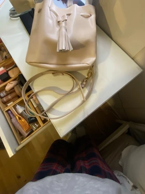 Beige bucket bag från Au Printemps Paris - Säljer en snygg beige bucket bag från Au Printemps Paris, tillverkad i Italien i läder. Den har en innerficka med dragkedja och har medföljande långt axelband som går att ta av samt justera. Nyskick! 💞skriv för fler bilder eller frågor! Nypris-ca 1300