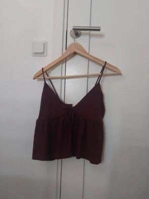 Vinröd linnetopp från Gina Tricot - Säljer en vinröd linnetopp från Gina Tricot i storlek S. Toppen har tunna axelband, v-ringad hals och en lätt utställd, flowy passform. Tröjan är cropped. Har sytt upp axelbanden lite.