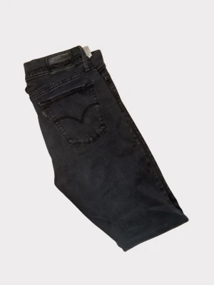 Svarta skinny jeans från Levi's - Svarta jeans från Levi's med klassisk femficksdesign och smal passform. Jeansen har en snygg, mörk tvätt och är tillverkade i stretchigt denim för extra komfort. Perfekt för dig som gillar en stilren och modern look.