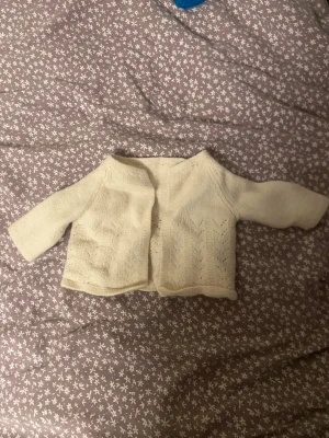 Vit stickad kofta med mönster - Söt vit stickad kofta med lång ärm och fint hålmönster framtill.