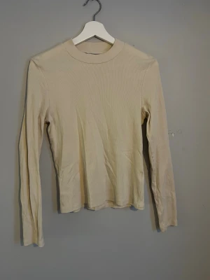 Ribbad top - Beige/cremevit topp. Aldrig använd men har legat i garderoben ett tag och är därför lite skrynklig. Inga skavanker annars.