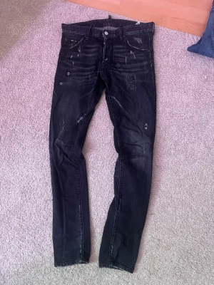 Dsquared2 jeans  - Säljer ett par svarta skinny jeans med coola slitningar och distressed detaljer. Jeansen har klassisk femficksdesign och är i stretchigt denimtyg för skön passform. Lappen vid gylfen finns kvar stoppat undan den bara