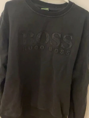 Svart sweatshirt från Hugo Boss XXL - Svart sweatshirt från Hugo Boss i storlek XXL. Tröjan har rund halsringning och ett stort broderat BOSS-logo på bröstet. Klassisk och enkel design med långa ärmar, perfekt för en chill och stilren look. Vid intresse skriv för mer info! ABS! Pris går att diskutera!