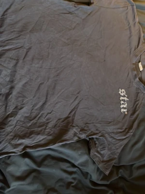 Svart t-shirt  - Cool svart t-shirt med tryck av en elgitarr med vingar och texten 'rock star' i stor stil på backsidan. T-shirten har korta ärmar. Perfekt för dig som gillar rockig stil och vill sticka ut lite extra.