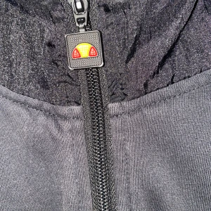 Svart hoodie med dragkedja - Snygg svart hoodie med dragkedja och huva. Den har ribbade muddar och en praktisk ficka framtill. Perfekt för en avslappnad stil.