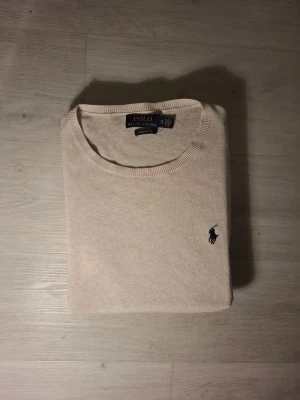 Beige tröja från Polo Ralph Lauren XS - Säljer en stilren beige tröja från Polo Ralph Lauren i mjuk pima bomull. Klassisk rund halsringning, långärmad och med den ikoniska mörkblå loggan broderad på bröstet. Perfekt för dig som gillar enkel och clean stil.