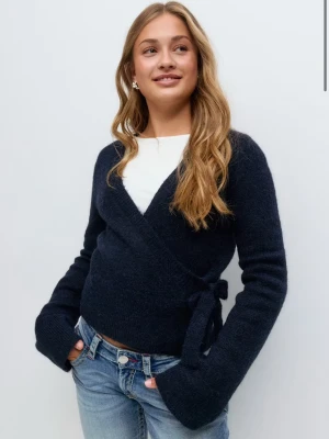 Mörkblå omlottkofta med knyt - Mörkblå stickad omlottkofta med knyt i sidan från Gina Tricot. Helt ny och oanvänd!