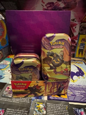 Pokémon TCG: Shrouded Fable Mini Tin -Dusclops (Sealed) - Helt ny och fabriksförseglad (Sealed) Pokémon Mini Tin från den populära serien Shrouded Fable! Denna stilrena plåtask pryds av motivet med Dusclops och är ett måste för både samlare och spelare. Den är perfekt att förvara dina favoritkort i eller som en del av en komplett set-samling.  Mini Tin innehåller: • 2 st Pokémon TCG: Shrouded Fable Booster Packs (Varje paket innehåller 10 kort och 1 Basic Energy). • 1 st klistermärkesark (Sticker sheet). • 1 st Pokémon-motivkort som visar konsten från 