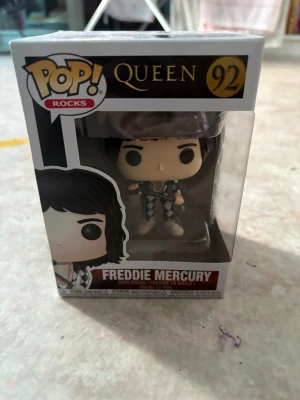 Queen Funko Pop-stil - Säljer en ikonisk svartvit rutig väst inspirerad av Freddie Mercury från Queen, i Funko Pop-stil. Västen har ett coolt harlekinmönster och är ärmlös med klassisk passform. Perfekt för dig som vill sticka ut med en unik och retro look. Lådan är lite skadad 