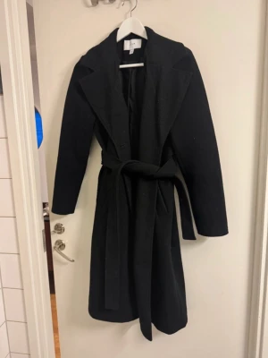 Svart lång kappa - VILA💕 -   ✨ Underbar lång kappa från VILA – storlek XS ✨  Säljer en superfin, mjuk och mysig lång kappa från VILA 🤍 Köpt via Vinted men endast provad – ångrade köpet och låter den därför hitta ett nytt kärleksfullt hem 💕  Kappan har en tidlös och feminin design, känns väldigt bekväm och sitter jättefint i storlek XS. Den knyts i midjan för en smickrande och gullig silhuett och har dessutom knappar framtill, så den kan bäras både öppet och stängt beroende på look ✨  Perfekt till höst och vinter – lika 