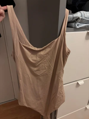 Beige body  - Säljer en enkel och stilren beige body, säljer för den aldrig kommer till användning. Aldrig använd prislappen är kvar! 