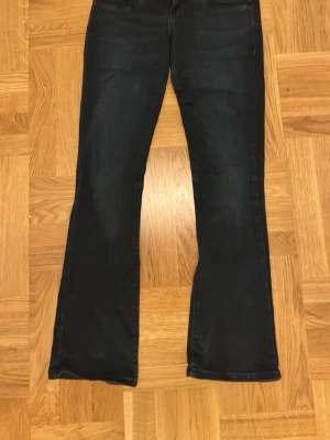 Mörkblå bootcut jeans från LTB - Säljer ett par mörkblå jeans från LTB i modellen Valerie. Byxorna har låg midja och bootcut-ben, med klassiska fem fickor och snygga sömdetaljer. Materialet är jeans och färgen är mörk, nästan svart. Perfekta för dig som gillar en retrovibe.