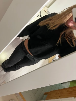 Svart croppad stickad tröja - Säljer en svart croppad stickad tröja med lång ärm. Tröjan har en mjuk och fluffig känsla, perfekt för dig som gillar en enkel men ändå cozy look. Passar till både jeans och kjol för en chill outfit.