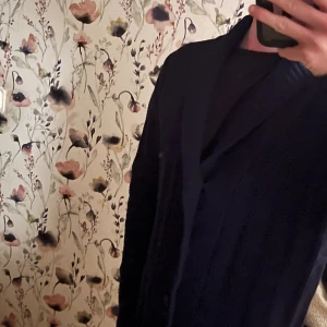 Mörkblå cardigan - Snygg mörkblå cardigan med klassisk krage och enkel knäppning framtill. Passar perfekt för dig som gillar stilrena och tidlösa plagg. Kavajen har en normal passform och är lätt att matcha med både skjorta och t-shirt.