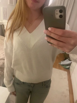 Vit ribbad stickad tröja med v-ringning - Säljer en fräsch vit stickad tröja med snygg v-ringning och ribbad struktur. Tröjan har lång ärm och en relaxed passform som är både chill och stilren. Perfekt att matcha med jeans eller kjol för en clean look. 