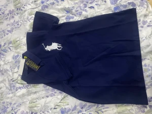 Mörkblå pikétröja Polo Ralph Lauren - Snygg mörkblå pikétröja från Polo Ralph Lauren med klassisk krage och knappslå. Stor vit broderad polospelare på bröstet och en vit siffra 3 på ena ärmen. Tröjan är gjord i mjuk bomull och har korta ärmar, perfekt för en clean och sportig look.