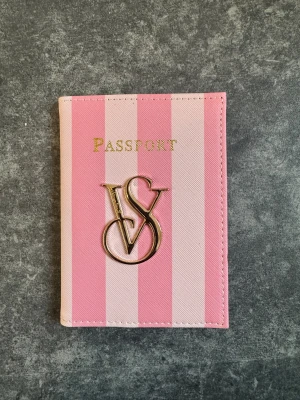 Randig rosa passfodral från Victoria's Secret - Snyggt passfodral från Victoria's Secret i rosa och ljusrosa ränder med guldfärgat VS-emblem på framsidan. Så fin julklapp till någon som reser mycket eller till sig själv 😍🩷. Prislapp kvar