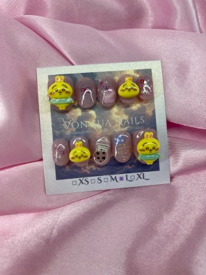 Usagi (L);ExtraShortOval  - Handgjorda press on-naglar i extra kort oval form med rosa glitterbas, dekorerade med söta 3D-kaniner i gult och grönt, små rosetter, stjärnor och textdetaljer. Perfekt för dig som vill ha unika och lekfulla naglar med kawaii-vibe.L: 17 mm, 12,5 mm, 13 mm, 12 mm, 10 mm 