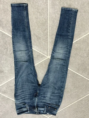 Jack & Jones mörkblåa jeans - Snygga blå jeans från Jack & Jones i skinny fit-modell. Jeansen har klassisk femficksdesign, slitningar och kontrastsömmar. Materialet är jeans med stretch för skön passform. Perfekt för dig som gillar smalare siluett och modern stil.