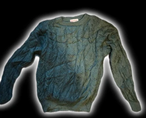 Mörkgrön stickad tröja Redford - Mysig mörkgrön stickad tröja från Redford med grovt kabelstickat mönster. Rund halsringning och långa ärmar, perfekt för att hålla värmen. Tröjan har ribbade muddar vid ärmslut och nederkant för extra komfort.