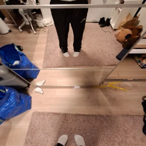 Svarta täckbyxor från Canadien - Svarta täckbyxor från Canadien med broderad logga på benet. Byxorna har en loose passform och är tillverkade i ett syntetmaterial som är perfekt för kalla dagar. De har dragkedja vid bensluten för enkel på- och avtagning. Perfekt för en Street style outfit