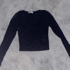 Svart croppad topp från FB Sister - Säljer en svart croppad topp från FB Sister i storlek XS. Toppen har långa ärmar och snygg snörning framtill som ger en cool detalj. Materialet är mjukt och stretchigt, perfekt för att skapa en trendig look. Passformen är tight och toppen har en rund hals.