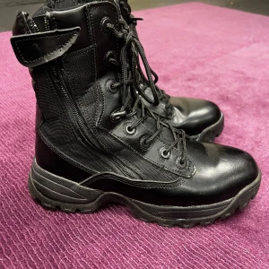 Svarta Mil-Tec kängor strl 42 - Svarta kängor från Mil-Tec i storlek 42 med grov mönstrad sula för extra grepp. Skorna har snörning, dragkedja på sidan och är tillverkade i en kombination av skinn och syntetmaterial. Perfekta för dig som gillar robust stil och funktion.