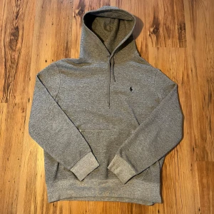 Grå hoodie från Polo Ralph Lauren - Grå Ralph lauren hoodie size M/175 🐎                Längd (66cm), bredd (48cm), ärm (59cm) 📏10/10 skick, inga defekter, använd 1-2 gånger Hör av er om ni har frågor 🤩